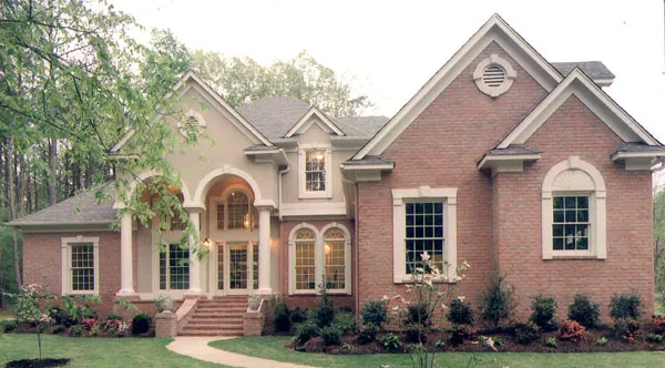 Two-Story Stucco Home With Arched Windows And Entry