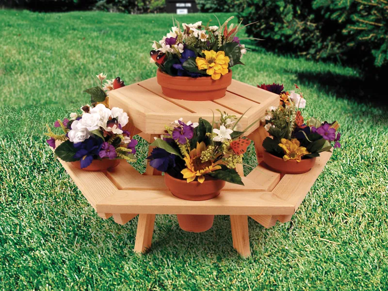 Small hexagon wood picnic table holds multiple clay flower pots